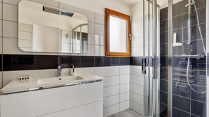 A modern bathroom with a white sink, a mirror, and a glass-enclosed shower area. - Homerez - House - Nevez, Enclosed (Nevez)