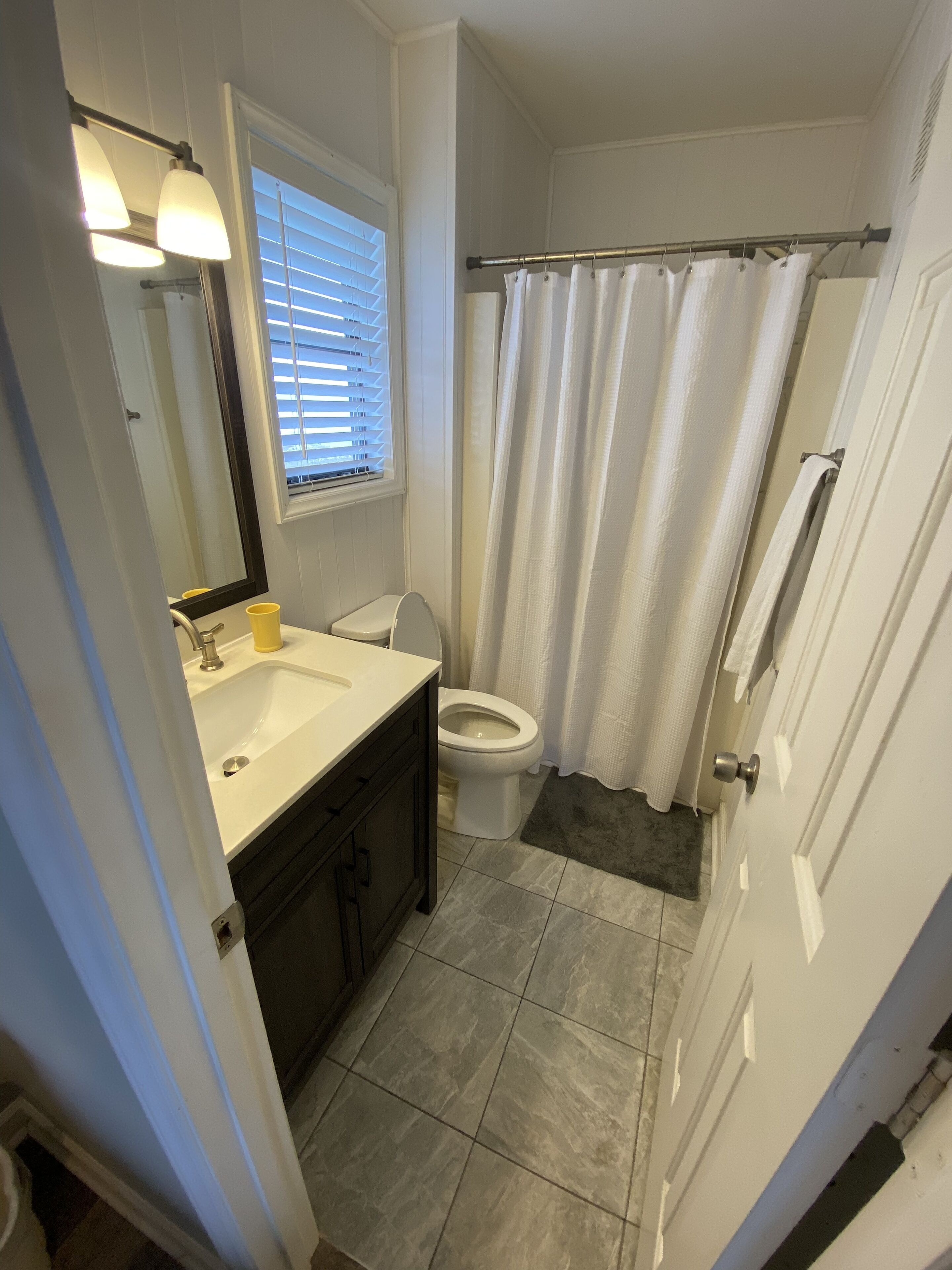 A bathroom with a white sink, dark cabinets, a toilet, and a shower curtain.