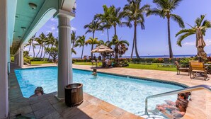 A pool area with a view of the ocean, palm trees, and lounge chairs. - Stunning Views & Tropical Tranquility 429 LS (Lahaina)