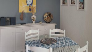 A dining area with a table set for four, white chairs, a decorative plate, and a wall-mounted picture frame.