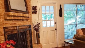 Uma sala de estar com lareira, uma porta e uma janela.