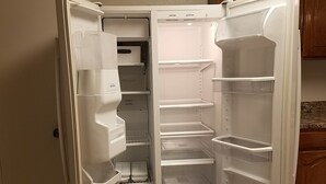 Geladeira aberta com várias prateleiras e compartimento congelador.