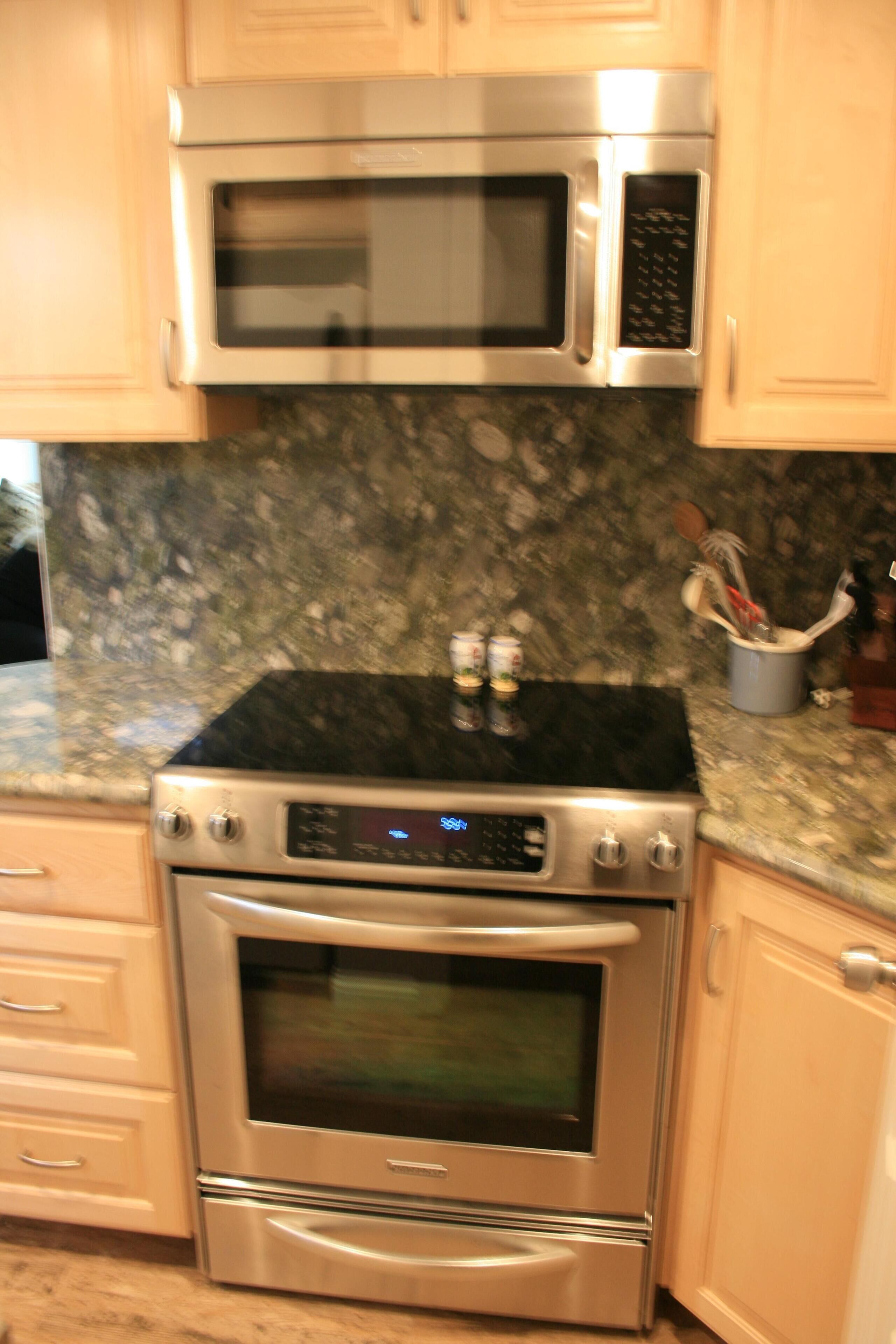 A kitchen with stainless steel appliances, including a microwave and oven, and wooden cabinets.
