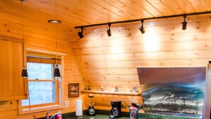 Une cuisine avec des murs en bois, un grand îlot central avec des tabourets, une cuisinière et un réfrigérateur.