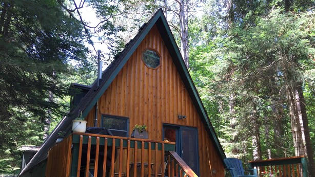 Une cabane en bois avec une véranda, des marches et une petite fenêtre.