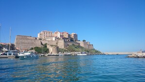 A coastal town with a prominent castle on a hill, boats docked along the waterfront, and a clear blue sky. - Fantastic apartment with sea views in prime location (Santa Reparata di Balagne)