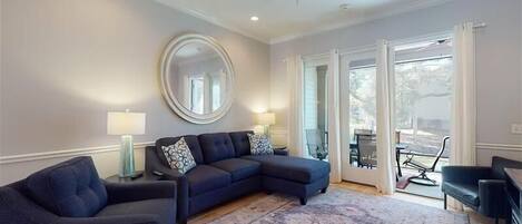 A living room with a sectional sofa, a round mirror, and a ceiling fan.