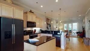 Une cuisine moderne dotée d’un îlot central, d’appareils électroménagers en acier inoxydable et de meubles de rangement en bois.