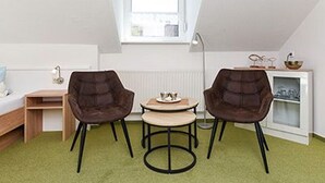 Et lille, hyggeligt værelse med en køjeseng, et skrivebord, to stole, et lille bord og en radiator.