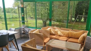 A covered outdoor seating area with wicker furniture and a view of a grassy landscape. - Your holidays in a beautiful property (Varaville)