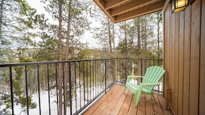A wooden deck with a green chair and a lantern, overlooking a snowy forest. - Beaver Village Unit #1824 Updated 2 bed close to downtown & outdoor activities (Winter Park)
