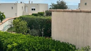 Ein Wohngebiet mit einem beigefarbenen Gebäude, grünen Büschen und blauem Himmel.