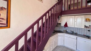 Eine Küche mit weißen Schränken, einer violetten Treppe und einem Bild an der Wand.