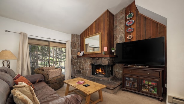 Una sala de estar con un sofá de cuero, una mesa de centro de madera, una chimenea y un televisor.