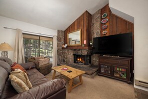 A living room with a leather sofa, a wooden coffee table, a fireplace, and a television.