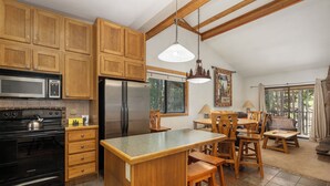 Una cocina con armarios de madera, un refrigerador de acero inoxidable, una estufa y una isla grande con taburetes de bar.