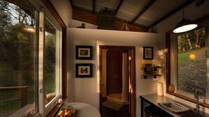 Une cuisine compacte avec un coin repas, une petite salle de bain et une vue sur l’extérieur.