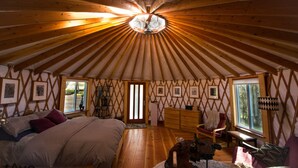 Une pièce spacieuse avec un plafond haut et des poutres en bois, un lit, un bureau et une chaise.