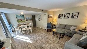 A living room with a dining area, a sofa, a coffee table, and a lamp. - Spacious, Updated Villa – Perfect for Family Beach Vacations, Two King Beds! (Hilton Head Island)
