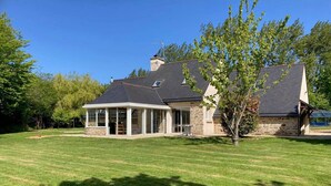 A two-story house with a stone facade, a large covered patio, and a well-maintained lawn.