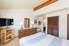 Une chambre à coucher comprenant un lit, une télévision, une commode, une chaise et une armoire.