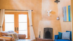 Ein gemütliches Wohnzimmer mit Kamin, einem blauen Sofa, einem Holzstuhl und einer Deckenleuchte.