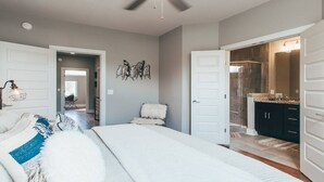 A bedroom with a bed, a ceiling fan, and a view into the bathroom. - Spacious Cowboy home near East Nashville with rooftop and views (Nashville)