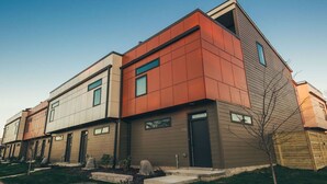 A modern multi-story residential building with a flat roof, large windows, and a well-maintained lawn. - Spacious Cowboy home near East Nashville with rooftop and views (Nashville)