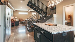 A modern kitchen with a granite countertop, a built-in stove, and a stainless steel refrigerator. - Spacious Cowboy home near East Nashville with rooftop and views (Nashville)