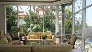 A spacious living room with a large window, a sofa, a coffee table, and a chair. - villa in the center of Funchal with pool and garden (Funchal)