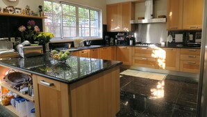 A modern kitchen with wooden cabinets, a black countertop, and a window providing natural light. - villa in the center of Funchal with pool and garden (Funchal)