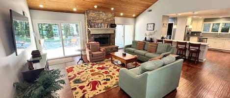 A spacious living room with a fireplace, a dining area, and a kitchen.