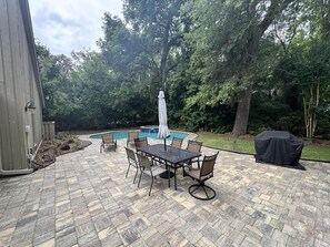 A patio with a pool, outdoor furniture, and a covered grill area.