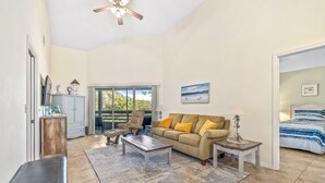 A spacious living room with a sofa, coffee table, and a ceiling fan. - Updated & Open, Sea Woods Veranda. Walking Distance to Beach - SV227 (New Smyrna Beach)