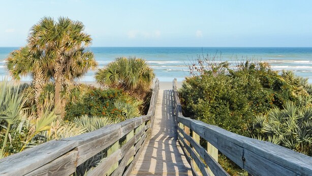 A wooden boardwalk leading to a beach with palm trees and ocean views. - Updated & Open, Sea Woods Veranda. Walking Distance to Beach - SV227 (New Smyrna Beach)