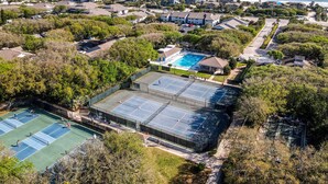 An aerial view of a residential area with a large swimming pool, tennis courts, and a view of the ocean. - Updated & Open, Sea Woods Veranda. Walking Distance to Beach - SV227 (New Smyrna Beach)