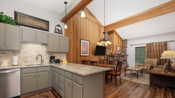 A kitchen with granite countertops, wooden cabinets, and a dining area with a table and chairs.