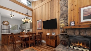 A wooden interior with a dining area, kitchen, and fireplace.