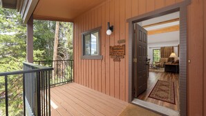 A wooden deck with a metal railing, a door leading to an interior room, and a sign on the wall.