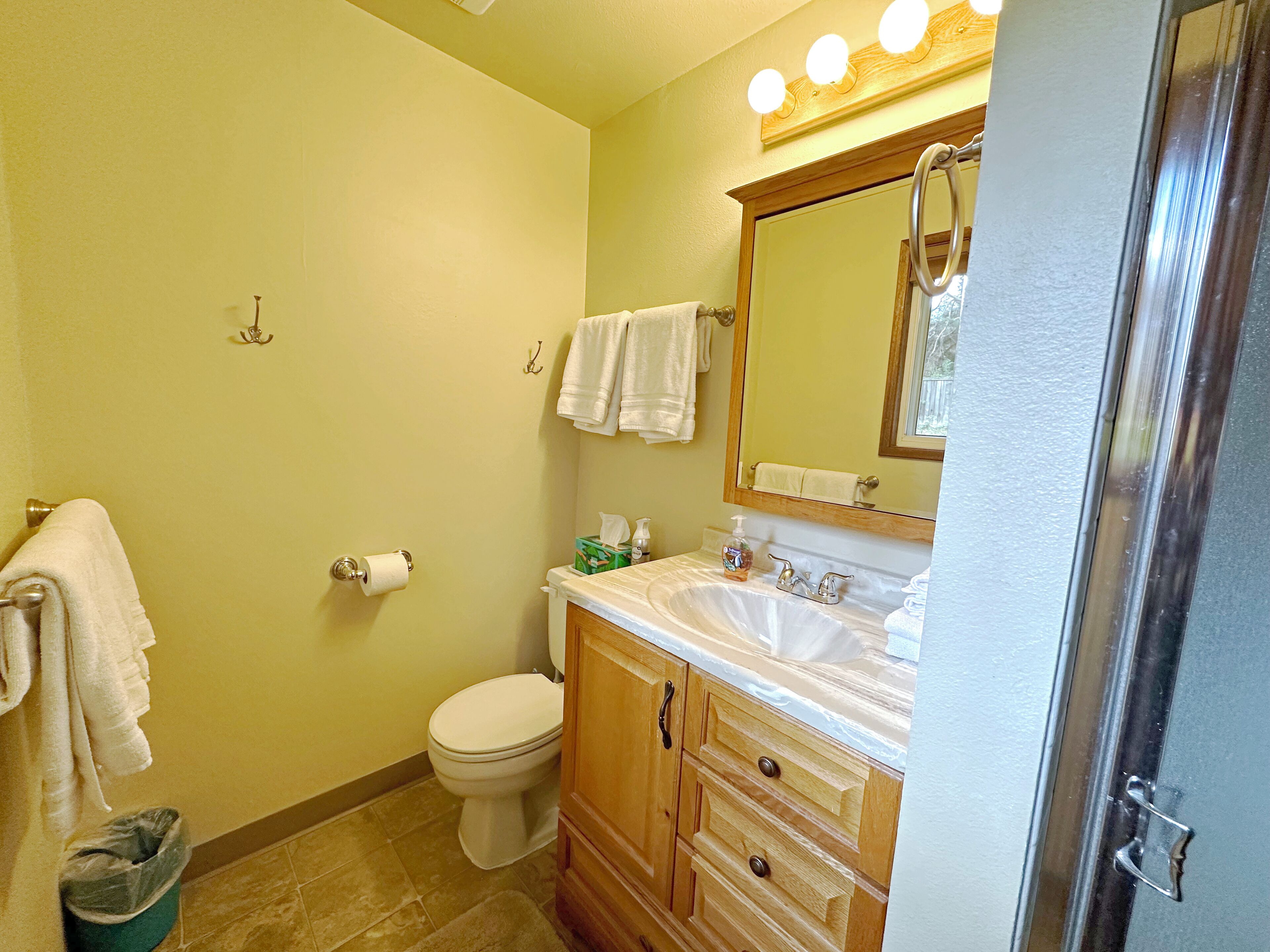 A bathroom with a toilet, sink, mirror, and towel rack.