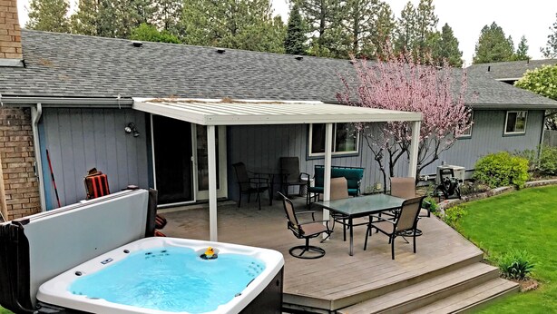 A backyard with a hot tub, patio furniture, and a covered seating area. - Premium 5 Bedroom Home-Theatre, BBQ, GYM, Hot-Tub and Arcade (Spokane)