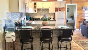 A kitchen with a central island, bar stools, and a refrigerator. - Large downstairs rental.1 bedroom.Full size kitchen.walk in shower No sharing  (Ruidoso)