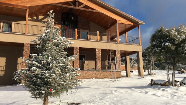 A two-story building with a wooden facade, a balcony on the upper floor, and a snow-covered ground. - Large downstairs rental.1 bedroom.Full size kitchen.walk in shower No sharing  (Ruidoso)