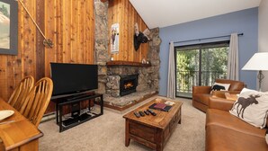 A cozy living room with a stone fireplace, a television, and a comfortable seating area. - Beaver Village Unit #1633 Classic 2 bed clean and comfortable with full kitchen (Winter Park)