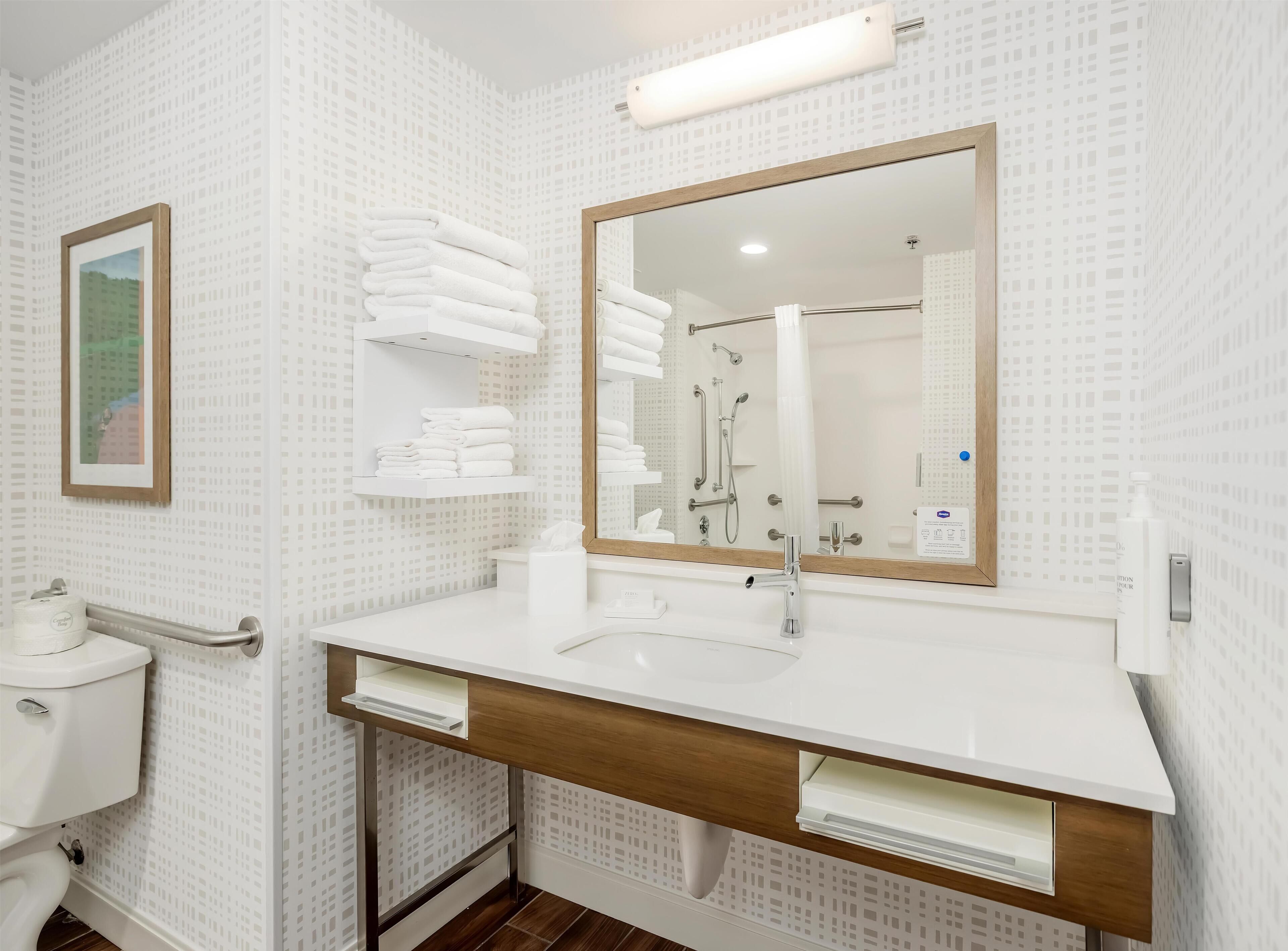 A modern bathroom with a white sink, mirror, and towel rack.
