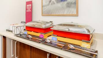 A buffet setup with labeled containers for cheese, sausage, and scrambled eggs.