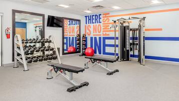 A gym with weightlifting equipment, a bench press, and a wall with motivational text.