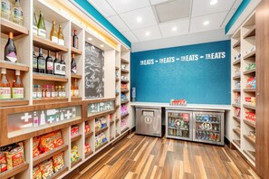 Un negozio con scaffali pieni di snack, bevande e un cartello che dice 'Treats'.