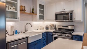 Une cuisine moderne avec des armoires blanches, une cuisinière en acier inoxydable, un four à micro-ondes et un évier.