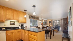 A kitchen with wooden cabinets, a central island, and a dining area with a table and chairs.
